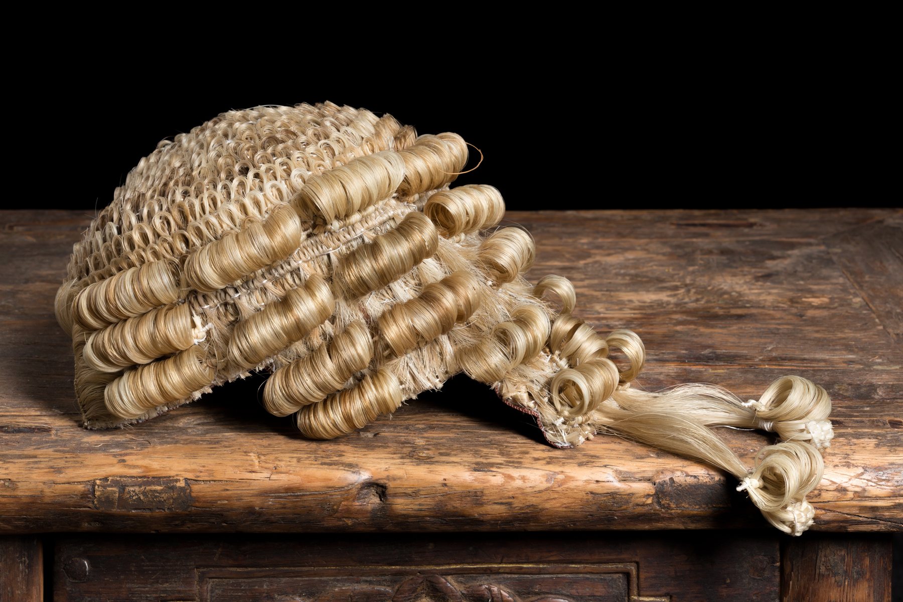 Traditional barrister’s wig resting on a wooden desk.